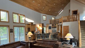 A spacious living area with leather sofas, a wooden coffee table, and a kitchen area with wooden cabinets and a stainless steel refrigerator. - Deepwater Lodge Chicagon Lake- Sleeps 24-Pontoon included-DM for June specials! (Crystal Falls)