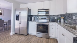 A modern kitchen with stainless steel appliances, white cabinetry, and a granite countertop. - Sleeps 6 Hot Tub Fenced Yard Cozy Chic (Tampa)
