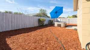 A backyard with a wooden fence, a blue umbrella, and a hose. - Sleeps 6 Hot Tub Fenced Yard Cozy Chic (Tampa)
