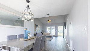 A modern dining area with a long table, chairs, and a chandelier. - Sleeps 6 Hot Tub Fenced Yard Cozy Chic (Tampa)