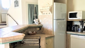 Una cocina con refrigerador, microondas y un colgador para ollas.