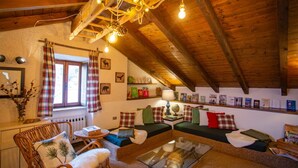 A cozy, rustic room with wooden beams, a fireplace, a sofa set, and a dining table. - The mountain loft with the most beautiful park on Lake Maggiore as its garden (TRAREGO VIGGIONA)