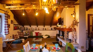 A cozy, rustic interior with a wooden ceiling, a dining area with a table set for two, and a living area with a sofa and a fireplace. - The mountain loft with the most beautiful park on Lake Maggiore as its garden (TRAREGO VIGGIONA)