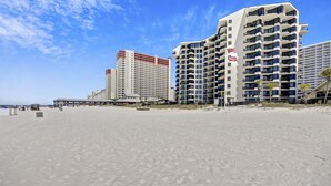 A beachfront hotel with multiple high-rise buildings, a sandy beach, and a clear blue sky.