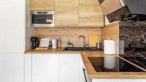 A modern kitchen with wooden cabinets, a built-in oven, a sink, and a marble backsplash. - Amazing flat, Paris suburb, near Versailles ,Orly (Orsay)