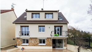 A two-story house with a stone facade, a balcony, and a small patio area. - Amazing flat, Paris suburb, near Versailles ,Orly (Orsay)