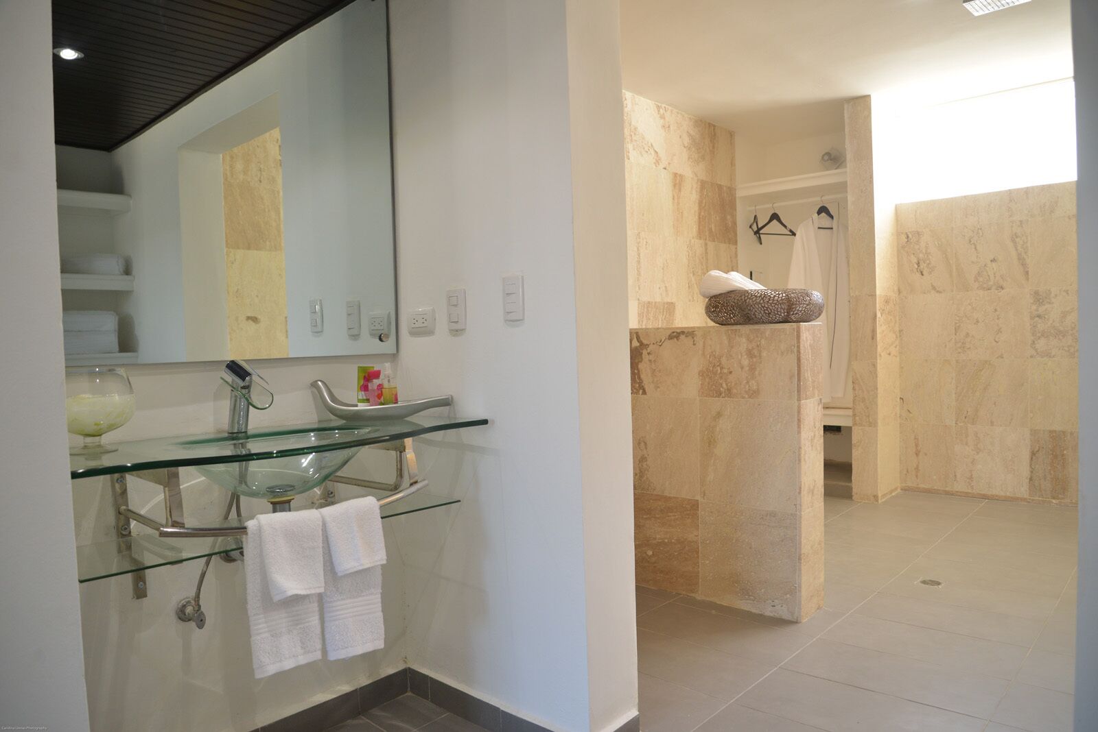 A modern bathroom with a glass sink, a large mirror, and a shower area.