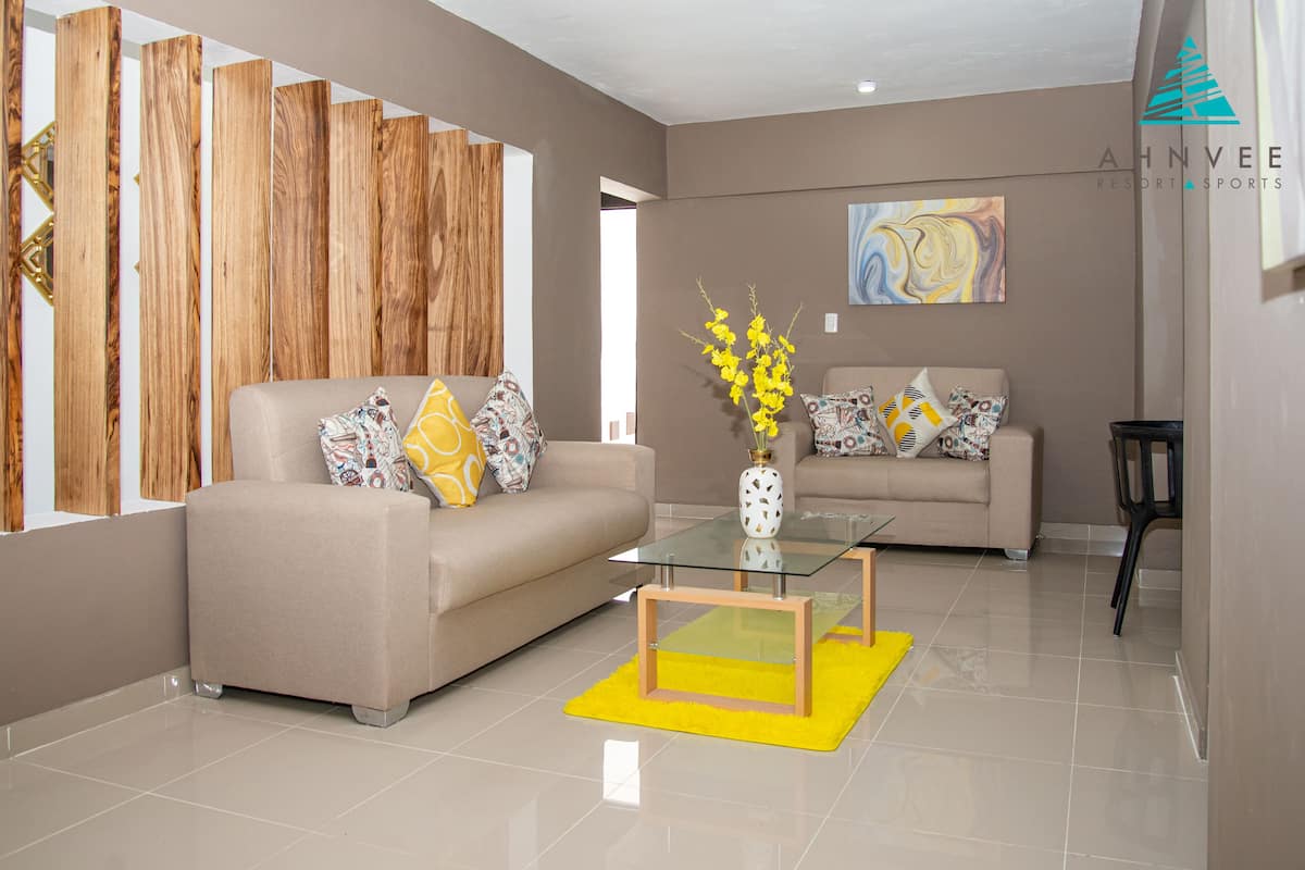 Un salon moderne avec deux canapés, une table basse en verre et un tapis jaune.