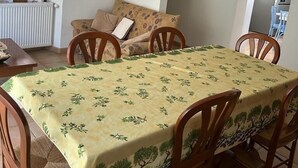 Een eetgedeelte met een tafel bedekt met een tafelkleed met bloemenprint, omringd door houten stoelen.