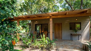 Ein überdachter Außenbereich mit Steinboden, einer Holzpergola und einer Tür zu einem Innenraum.