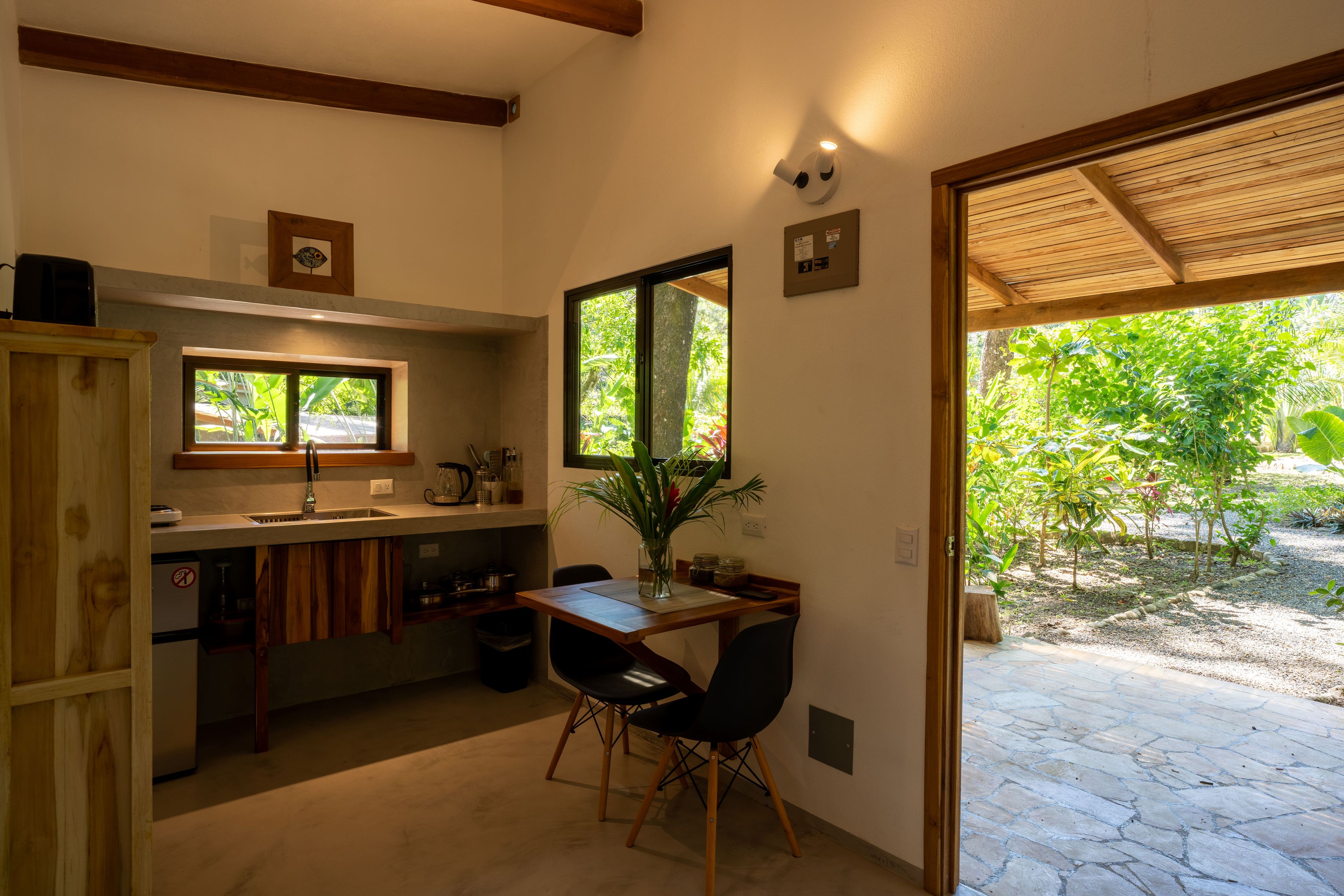 Cocina compacta con comedor, ventana con vistas a zonas verdes y puerta que da a un patio exterior.