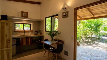Cocina compacta con comedor, ventana con vistas a zonas verdes y puerta que da a un patio exterior.