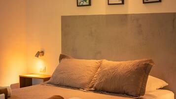A neatly made bed with a headboard, a bedside lamp, and three framed pictures on the wall.