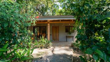 A house with a covered porch, a gravel path leading to the entrance, and lush greenery surrounding the property.