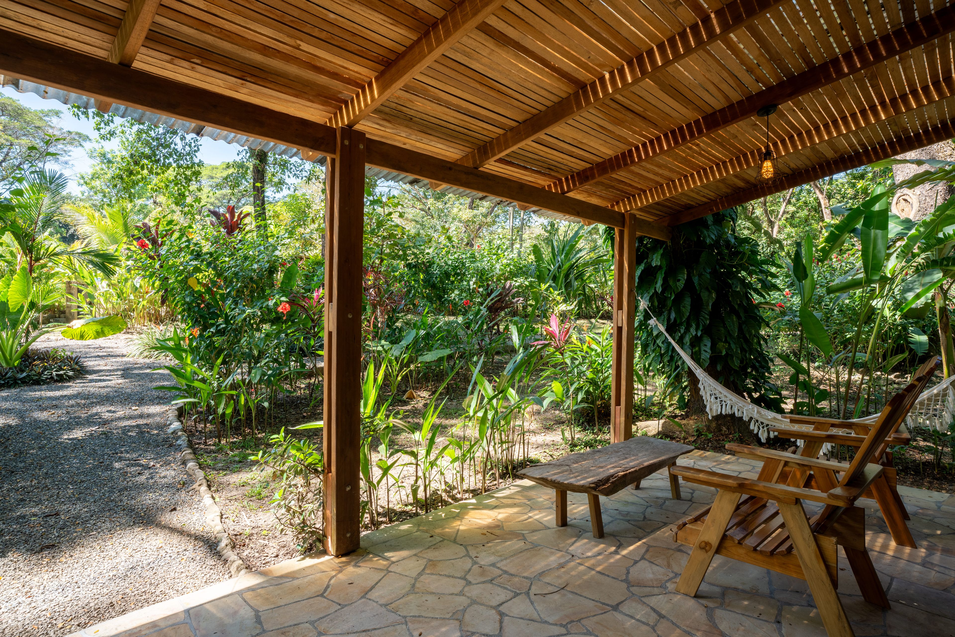Un espace extérieur aménagé, abrité et doté d’un hamac et de mobilier en bois.