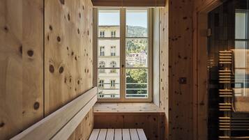 A wooden cabin with a window overlooking a building and trees.