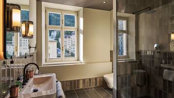 Une salle de bain moderne dotée d’une grande fenêtre, d’une douche à parois de verre et d’un lavabo avec des articles de toilette.