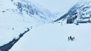 A snow-covered mountain landscape with a building and a few people walking.