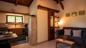 Un espacio de sala acogedor con un sofá, una mesita de centro y una zona de cocina con ventana.