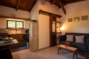 Un espacio de sala acogedor con un sofá, una mesita de centro y una zona de cocina con ventana.