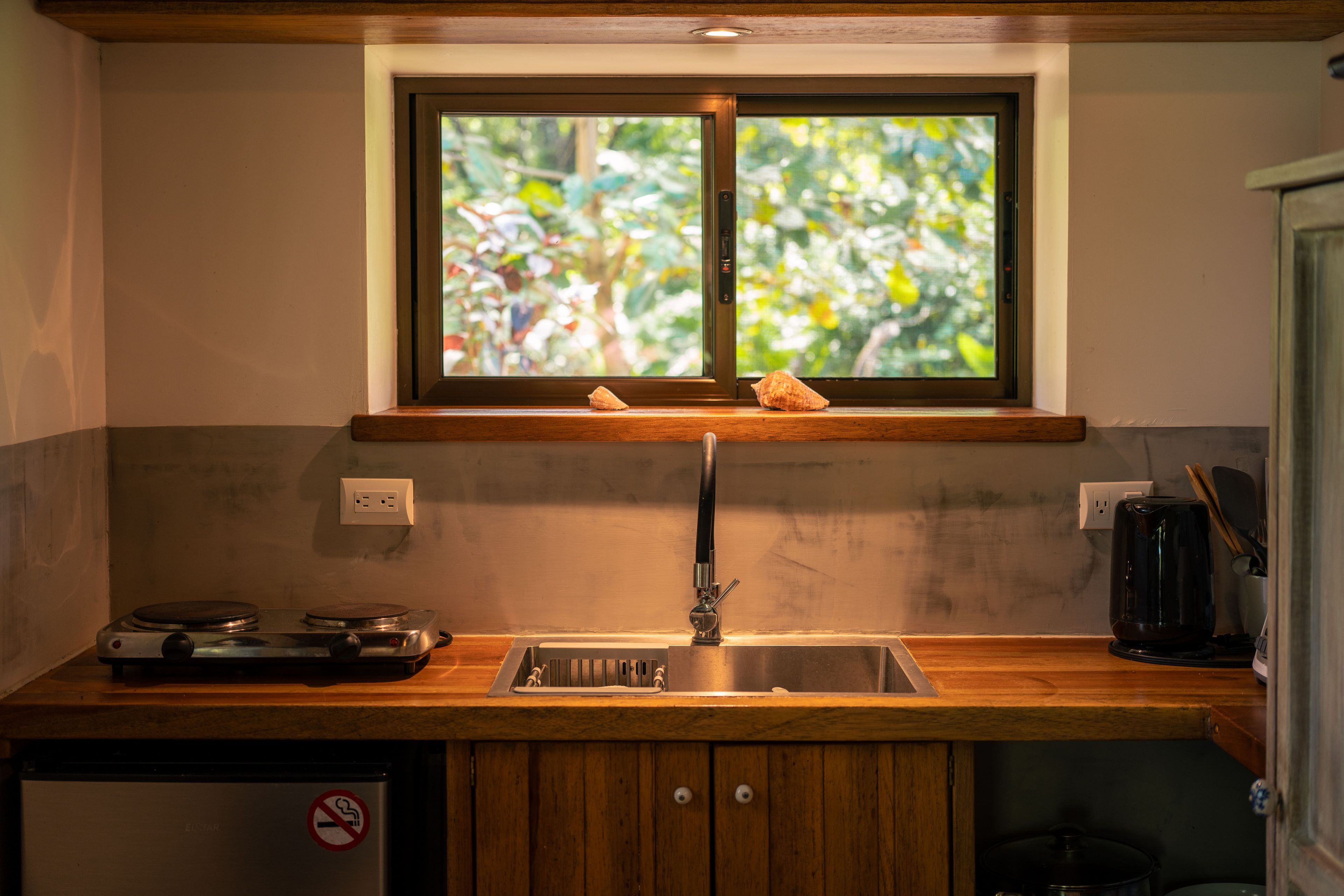 Una cocina con ventana, un lavamanos, una estufa y armarios.