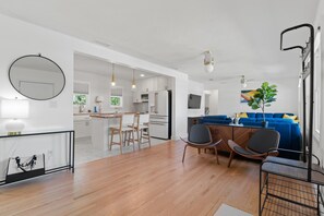 Cozy living space with a round mirror, dining area, and seating area featuring a sofa and potted plant.