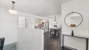 Un interior moderno con comedor, cocina y un espejo grande en la pared.