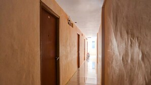 A long, narrow hallway with multiple doors on one side and a tiled floor. - Hotel O Hasan House SyariahNearPelabuhan Feri Harbor Bay (Batam)