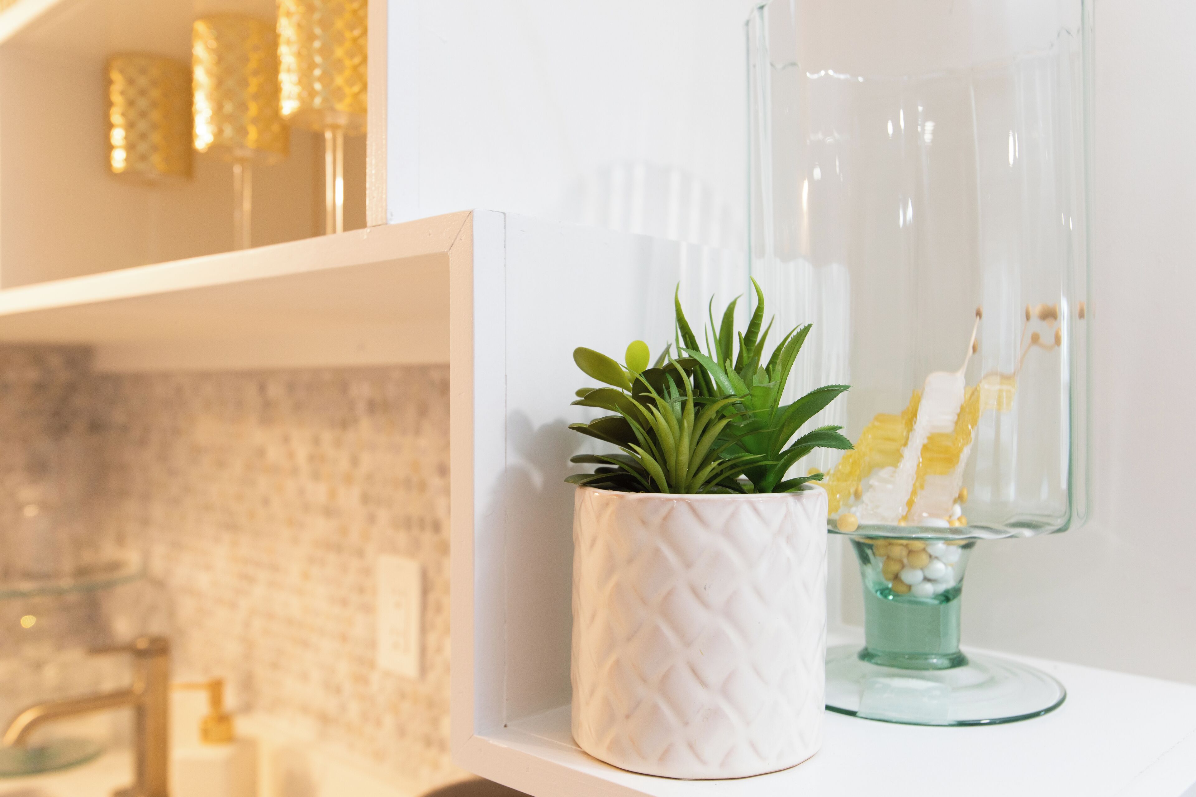 A white shelf with a potted plant and a glass dessert stand.