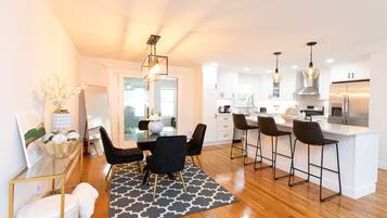 A modern kitchen with white cabinets, a central island with bar stools, and pendant lighting.