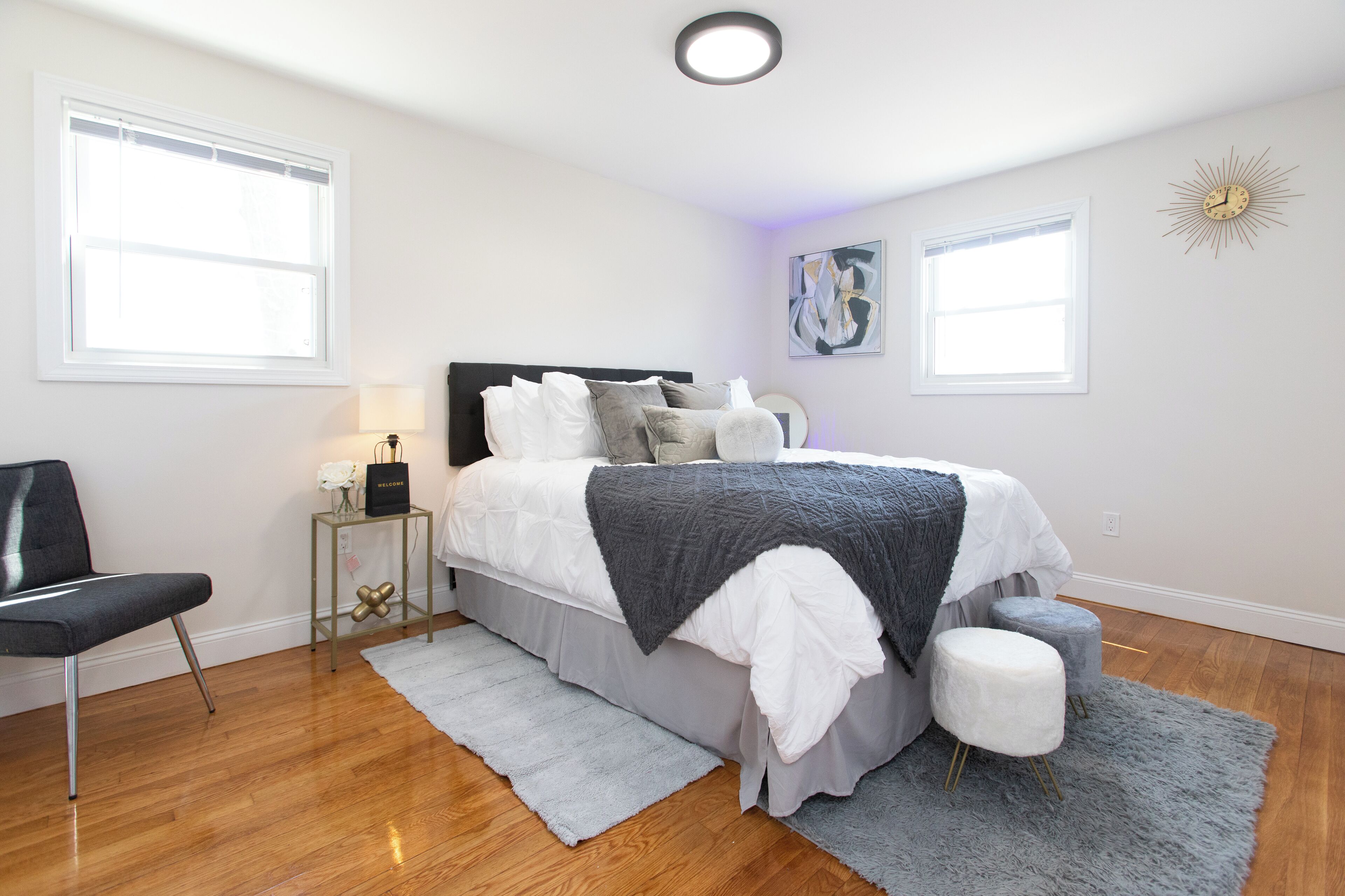 A bedroom with a bed, a chair, a nightstand, and a wall clock.