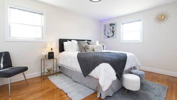 A bedroom with a bed, a chair, a nightstand, and a wall clock.