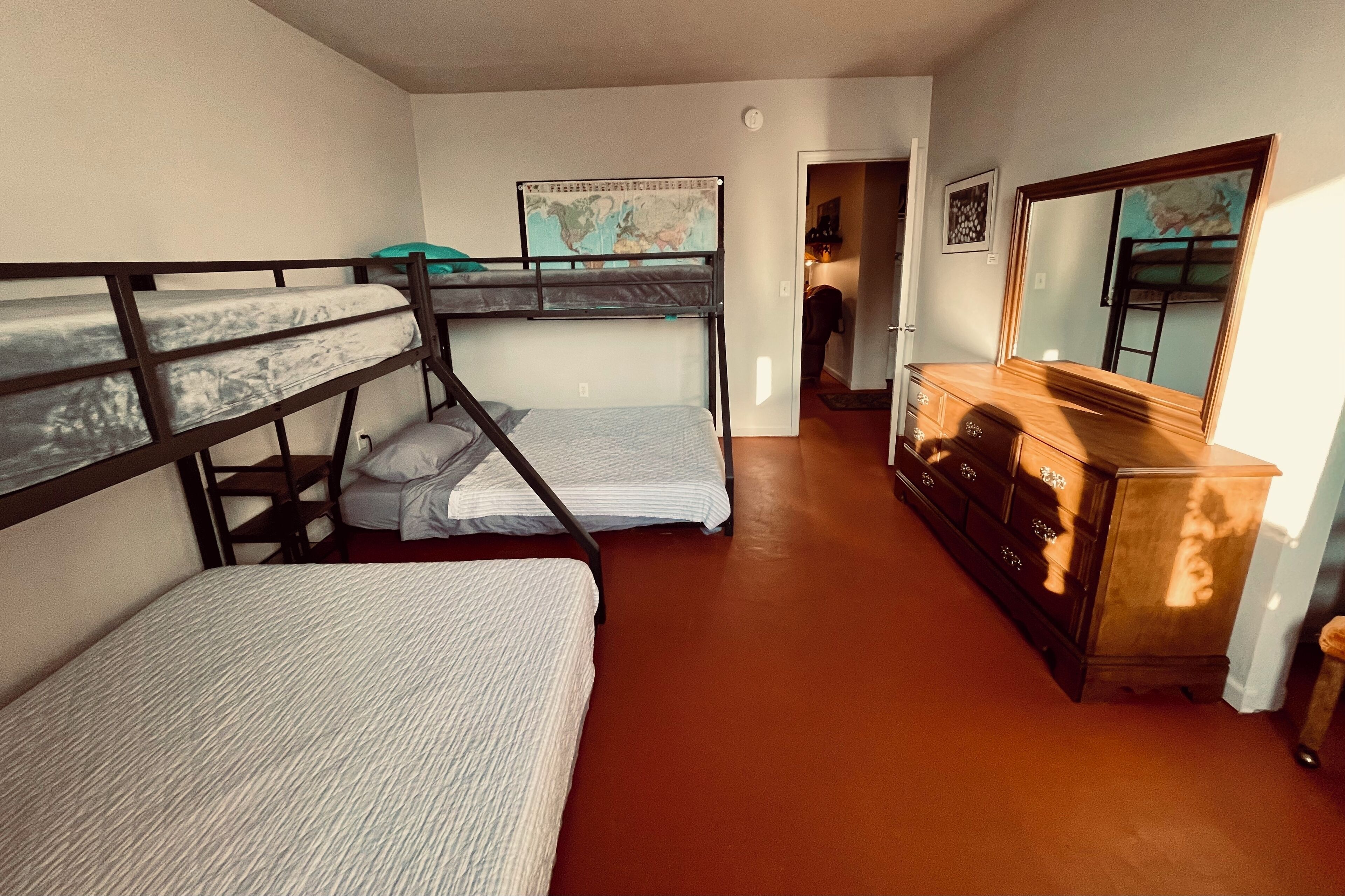 Una habitación con literas, un aparador, un espejo y un mapa en la pared.