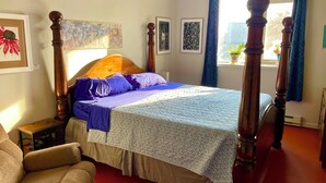 Ein Schlafzimmer mit Himmelbett, einem kleinen Nachttisch, einem Stuhl und einem Fenster mit Vorhängen.