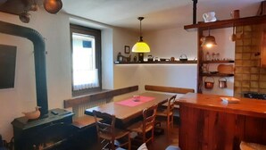 A cozy living room with a fireplace, wooden furniture, and a dining area. - Ursula House - Your Mountain Holiday (Premana)