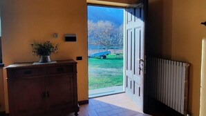 A hallway with a wooden cabinet, a radiator, and a door leading outside. - Cascina Cà Scarlatta - Your Mountain Holiday (Introbio)
