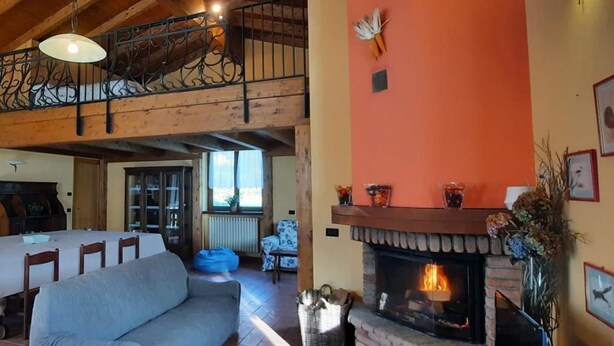 A spacious living area with a fireplace, a dining table, and a sofa. - Cascina Cà Scarlatta - Your Mountain Holiday (Introbio)