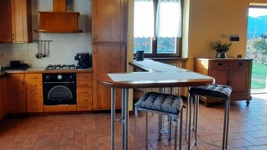 A kitchen with wooden cabinets, a gas stove, a sink, and a window with a view of the outdoors. - Cascina Cà Scarlatta - Your Mountain Holiday (Introbio)