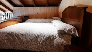 A bedroom with a wooden headboard, two beds with floral bedding, and a wooden wardrobe. - Cascina Cà Scarlatta - Your Mountain Holiday (Introbio)