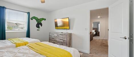 A bedroom with two beds, a ceiling fan, a TV, and a wardrobe.