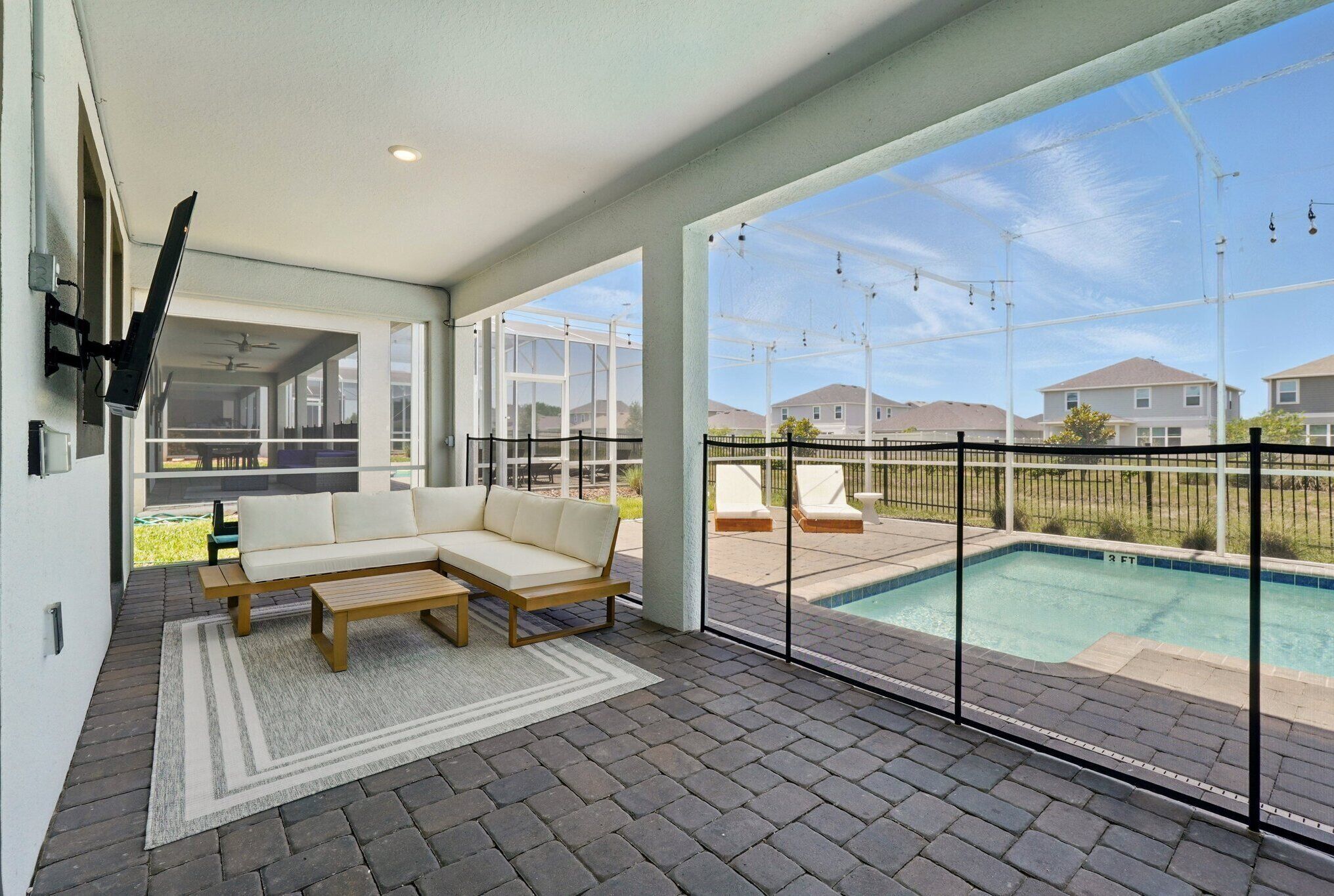A modern outdoor living area with a sectional sofa, a wooden coffee table, and a pool view.