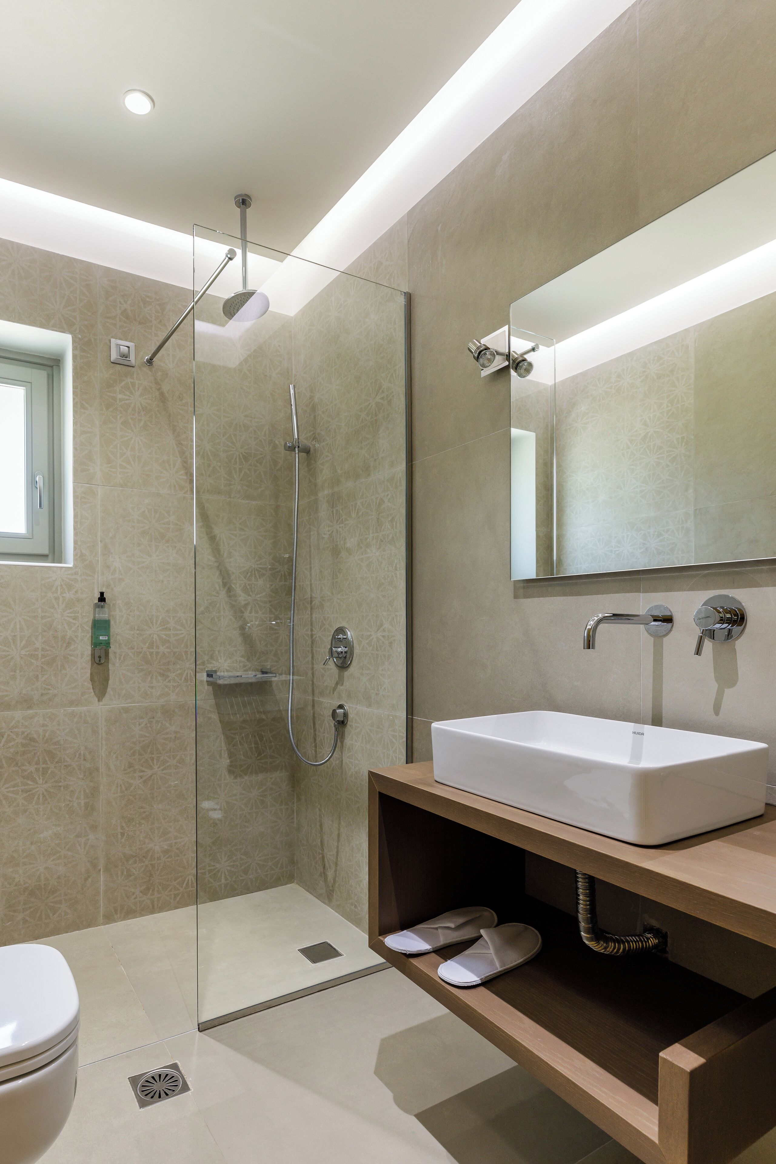 A modern bathroom with a glass-enclosed shower, a white sink, and a mirror above it.