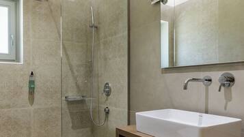 A modern bathroom with a glass-enclosed shower, a white sink, and a mirror above it.