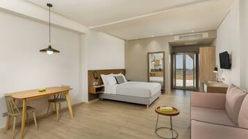 Una camera d'hotel moderna con un letto, una scrivania con sedie, un piccolo tavolo, un divano e vista sull'esterno.