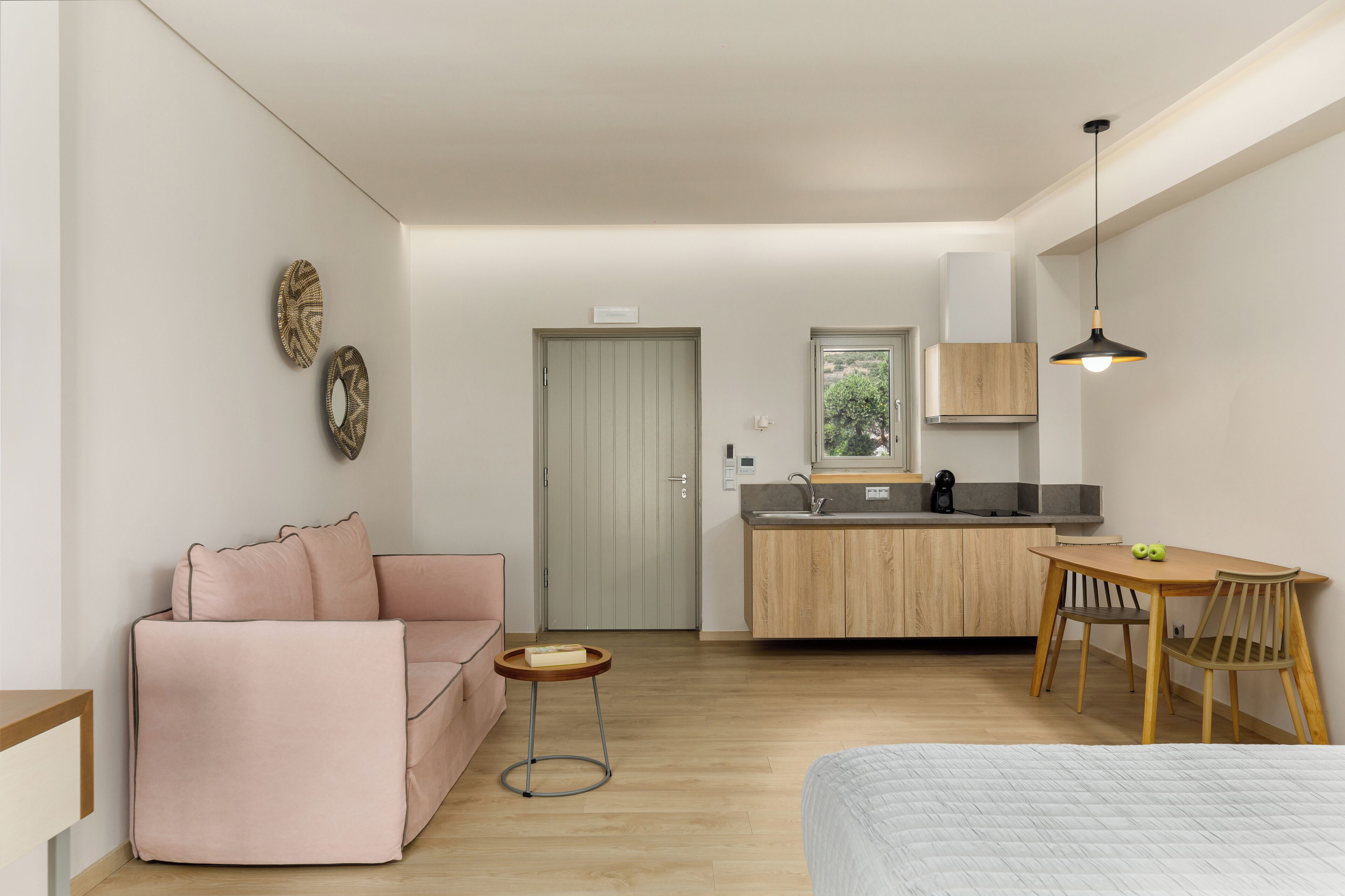 Un espacio habitable moderno y funcional, con kitchenette, sofá, mesa de comedor y cama.
