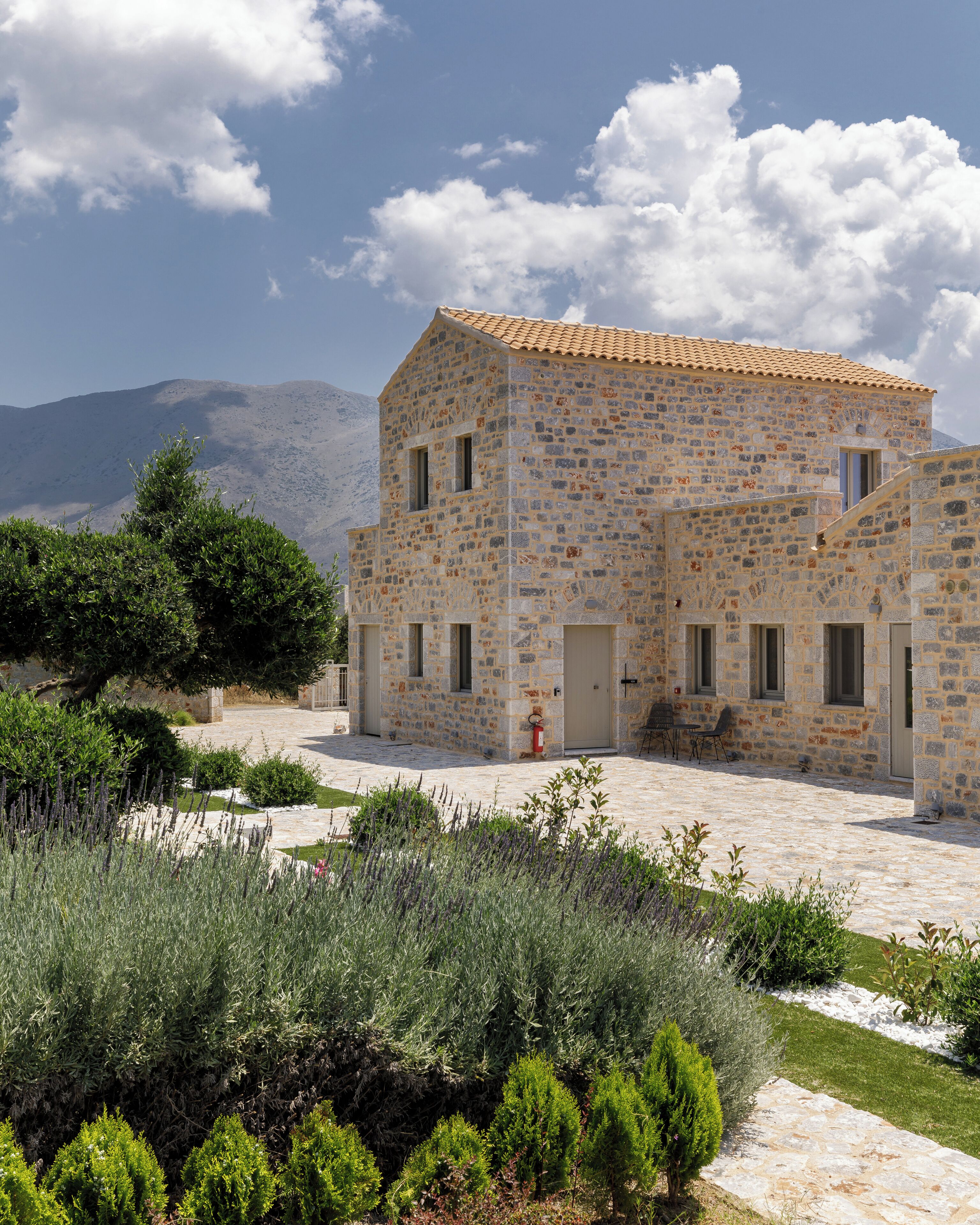 A stone building with a tiled roof, a door, and windows.