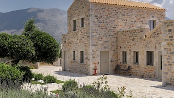 A stone building with a tiled roof, a door, and windows.