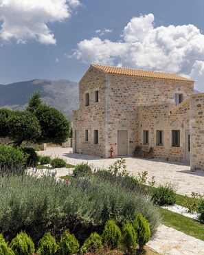 A stone building with a tiled roof, a door, and windows.