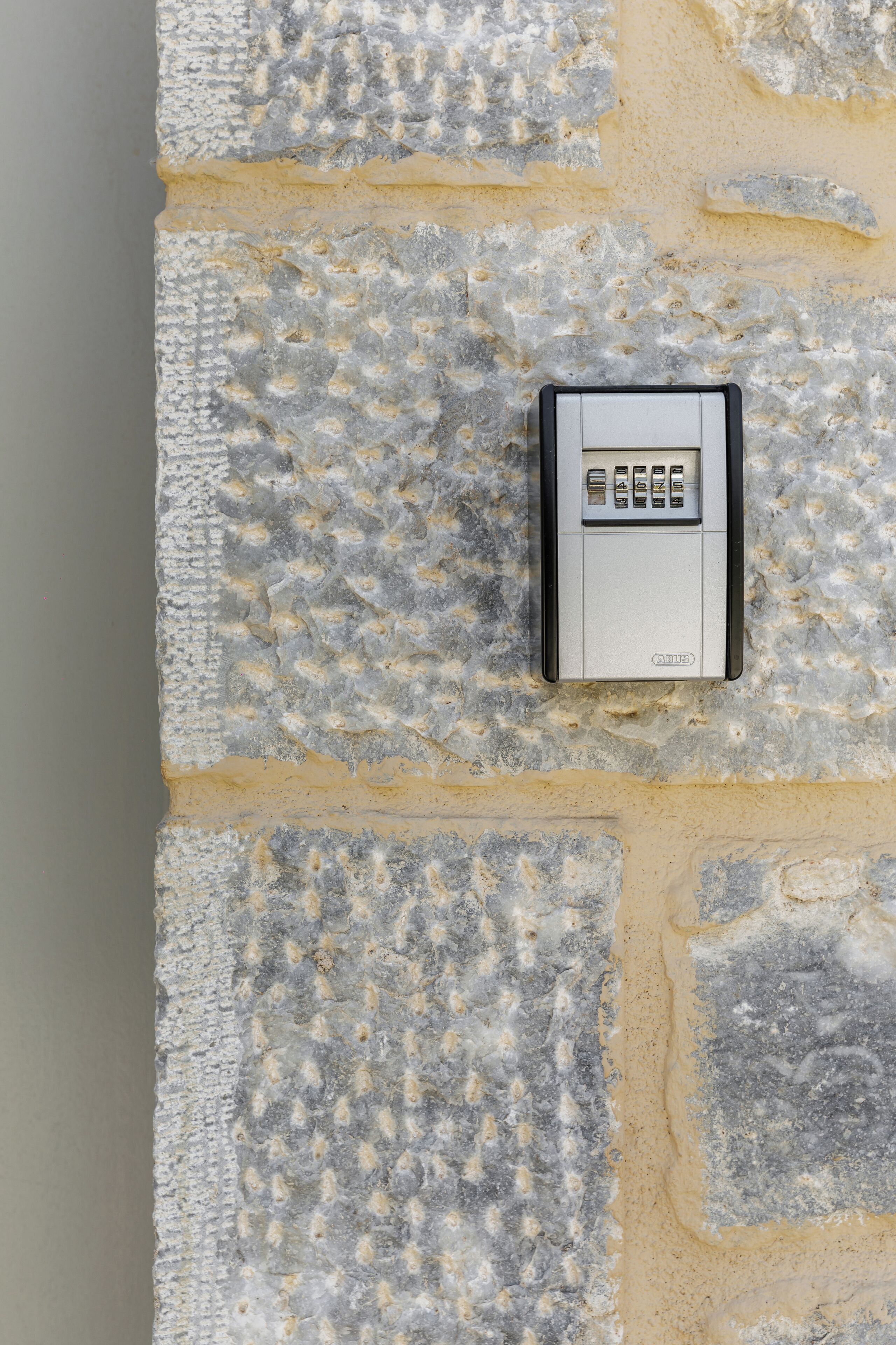 A keypad security device mounted on a textured stone wall.