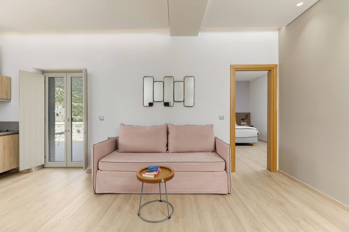 Ein modernes Wohnzimmer mit einer Couch, einem kleinen Tisch mit Büchern und einer Wandleuchte.